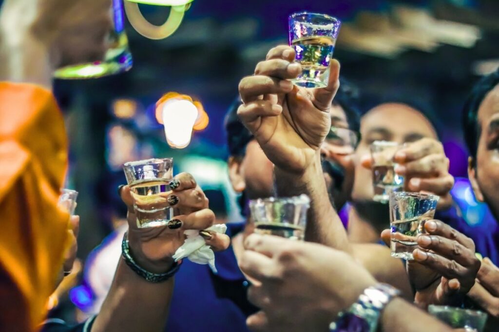 Group of young people cheering with alcohol shots.