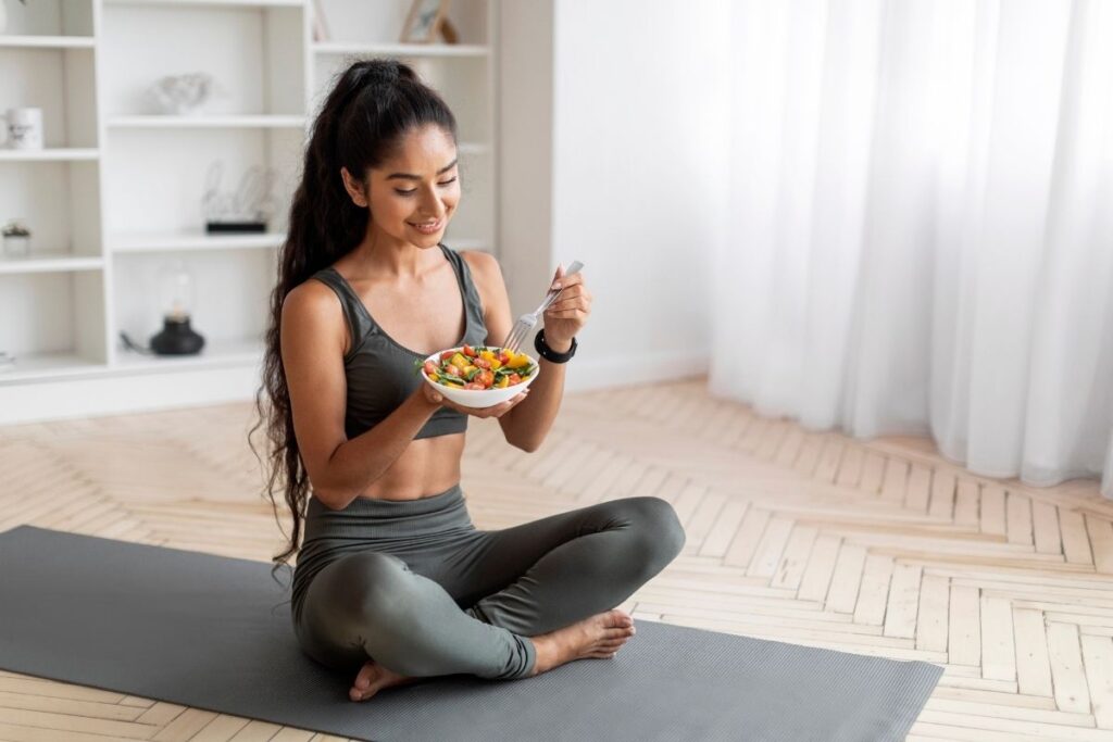 Young girl on a yoga mat eating a healthy meal during alcohol addiction recovery