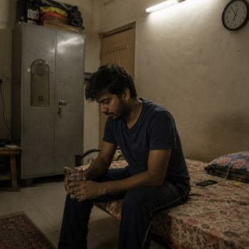 Person sitting alone in a room while coping with relapse triggers and rebuilding recovery habits.