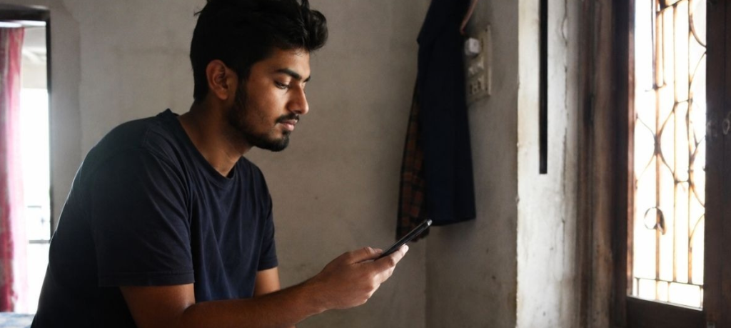 Young adult exploring Rehabilitation Centers That Offer Art Therapy, Music Therapy, and Sports Activities on a smartphone.