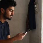 Young adult exploring Rehabilitation Centers That Offer Art Therapy, Music Therapy, and Sports Activities on a smartphone.